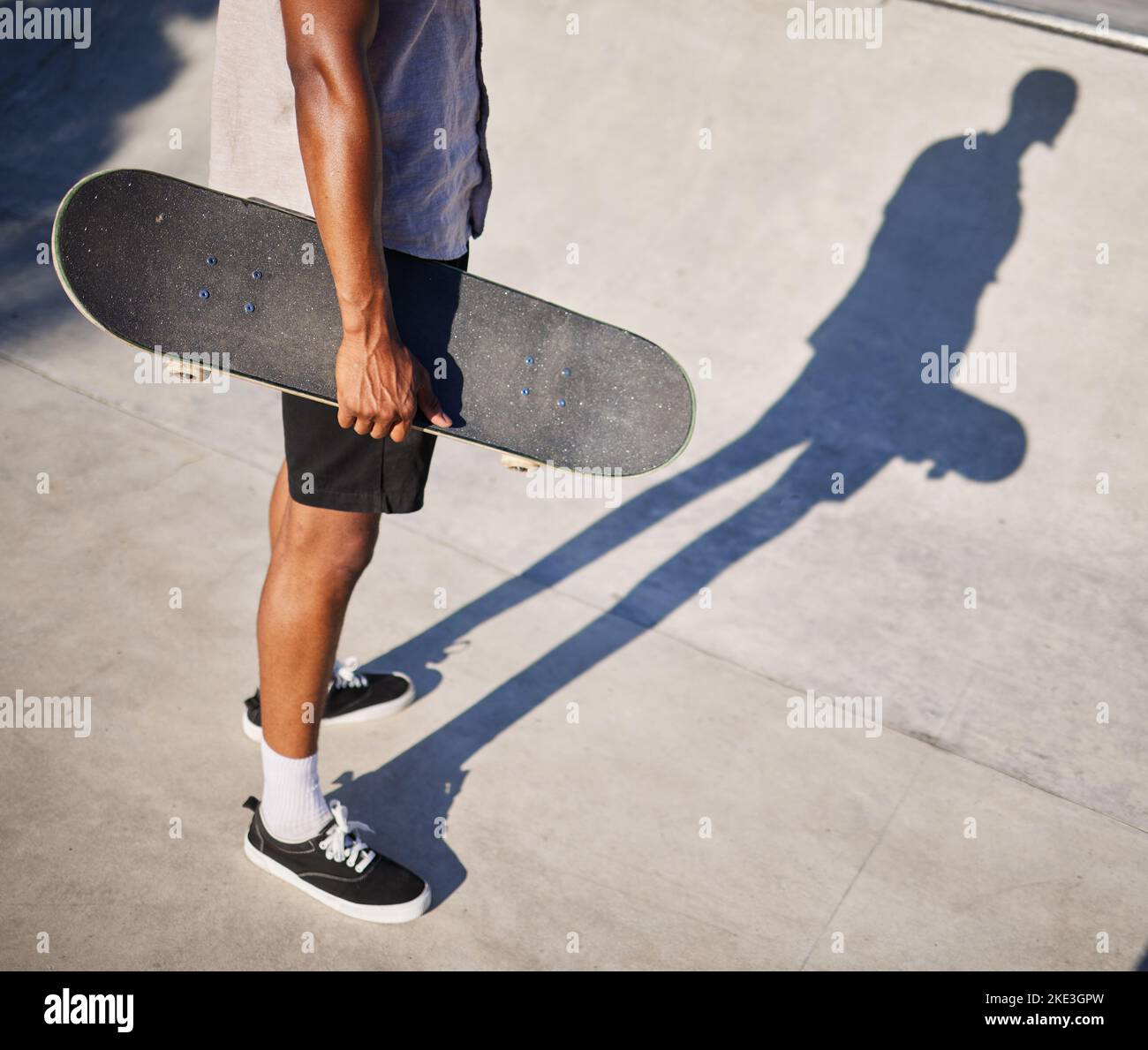 Skateboard, sport et homme tenant une planche pour s'amuser, faire de l'équitation et jouer dans un parc. Jambes, ombre et cool skater ou skateboarder patinage avec un Banque D'Images