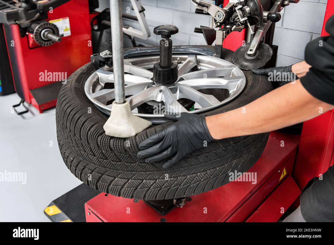 De dessus récolte homme ouvrier de garage en gants de démontage du pneu de la jante à l'aide de machines spéciales Banque D'Images