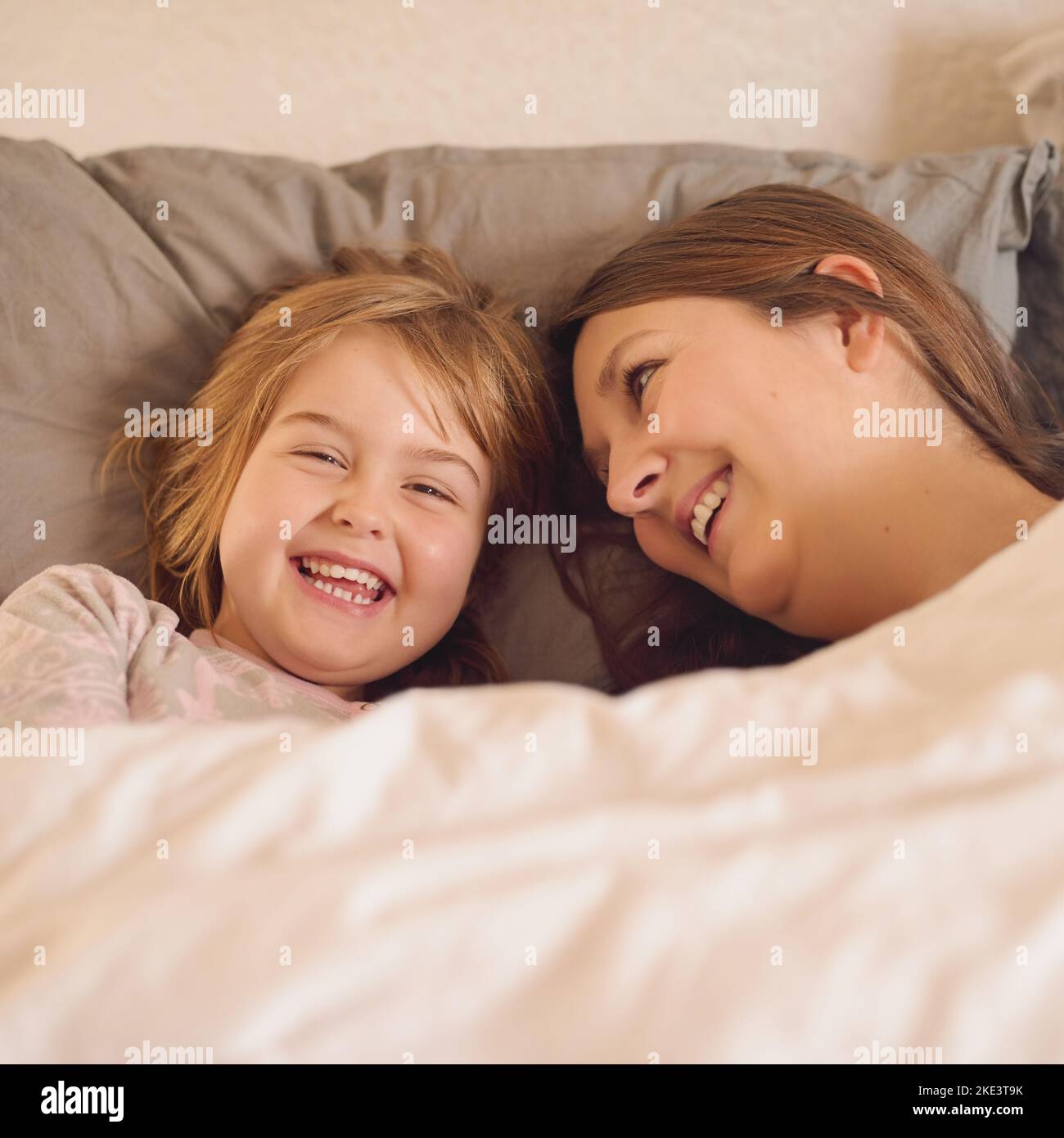 Lever et briller une mère et sa petite fille couchée au lit ensemble à la maison. Banque D'Images