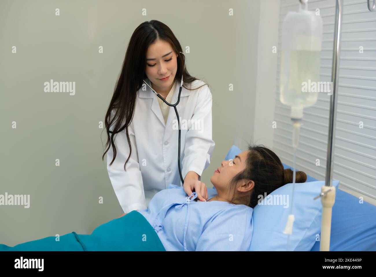 Souriante asiatique femme médecin utilisant stéthoscope à l'écoute vérifier le rythme cardiaque femme graisse patient sur le lit, examen et diagnostic. Banque D'Images