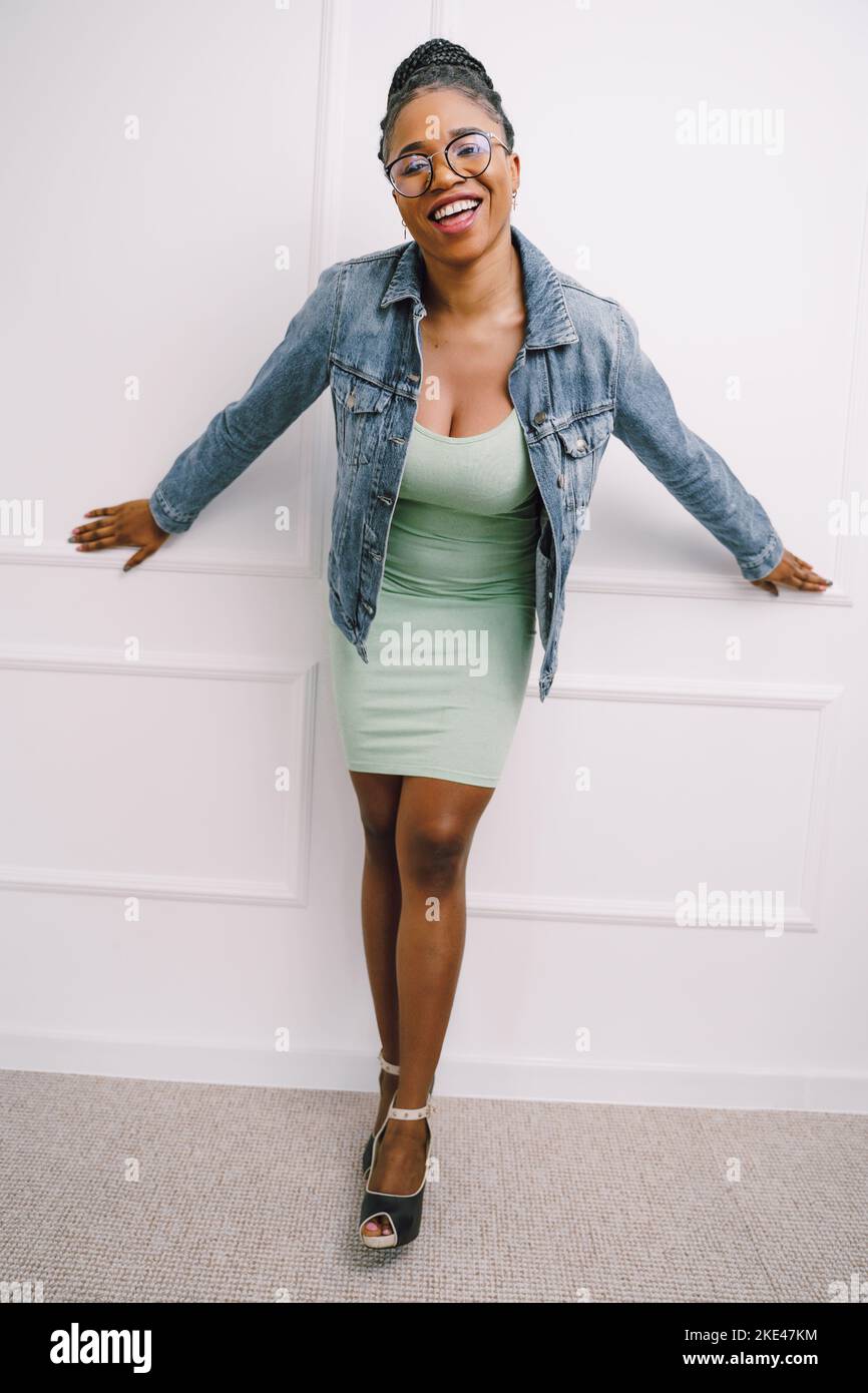Belle jeune femme afro-américaine portant une robe avec une veste jean souriante et excitée sur fond gris clair Banque D'Images