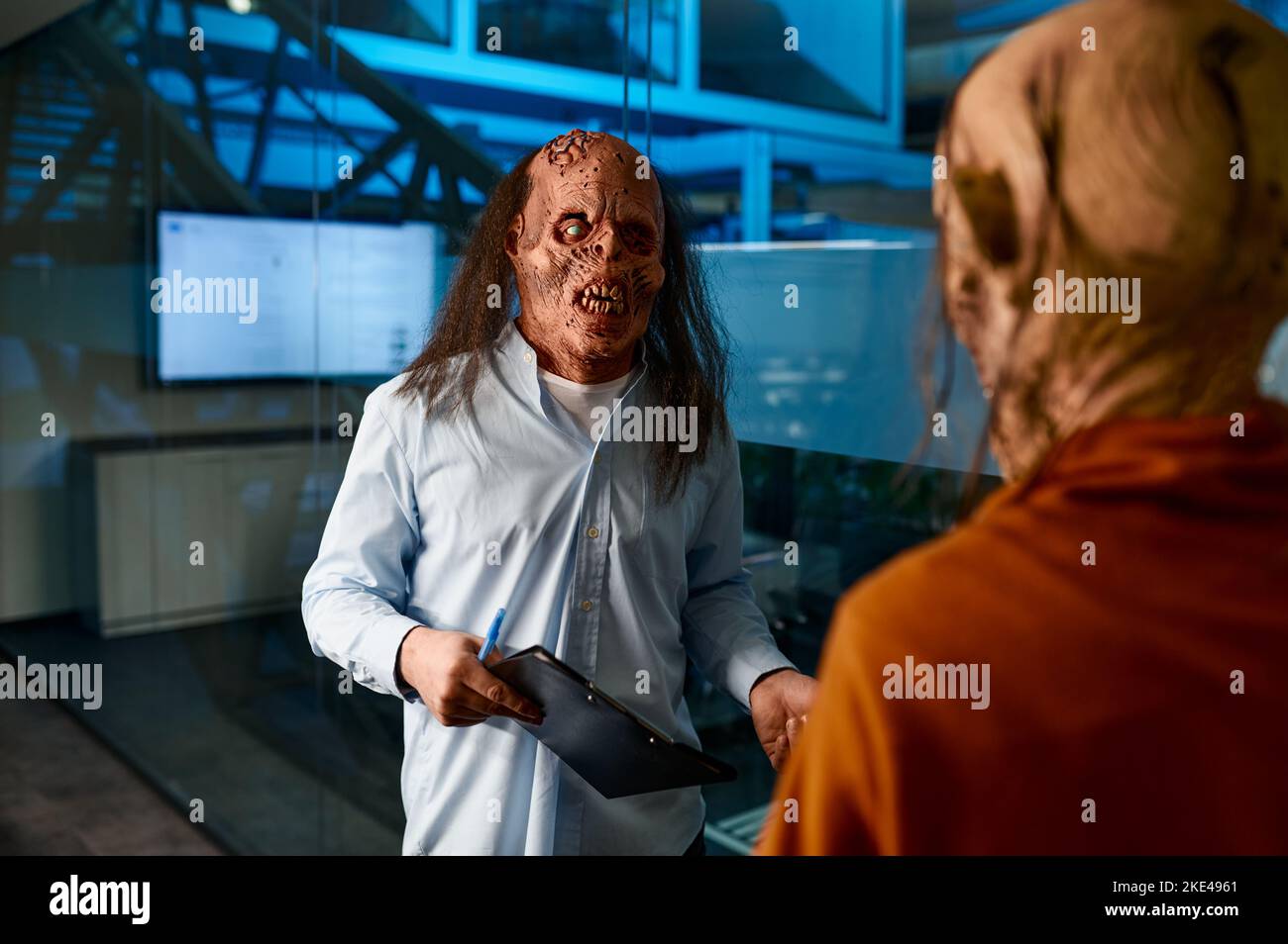 Des collègues zombies qui parlent debout dans la salle de conférence la nuit Banque D'Images