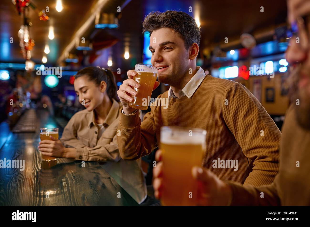 Les amis se reposent dans le bar sportif, se concentrent sur les jeunes hommes qui boivent de la bière Banque D'Images