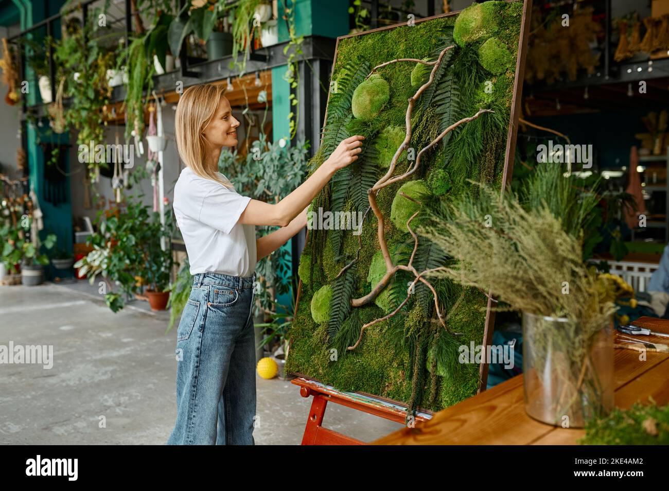 Jeune fleuriste heureux décorateur créant panneau de mousse de plante Banque D'Images