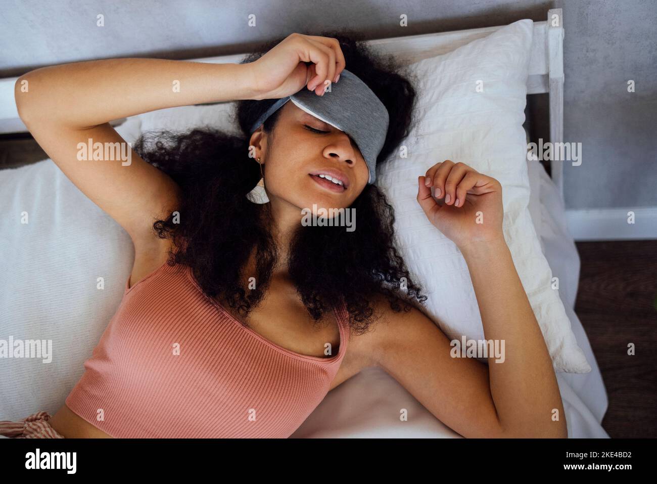 Jeune femme afro-américaine porte un pyjama endormi sur le lit à la maison, les yeux fermés, prenant une pause. Black Millenium girl reposant, vue du dessus. Détendez-vous Banque D'Images