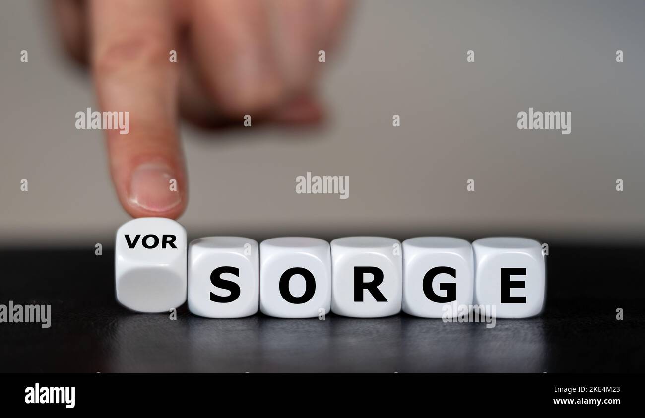 La main tourne les dés et change le mot allemand 'sorge' (problème) en 'Vorsorge' (précaution). Banque D'Images