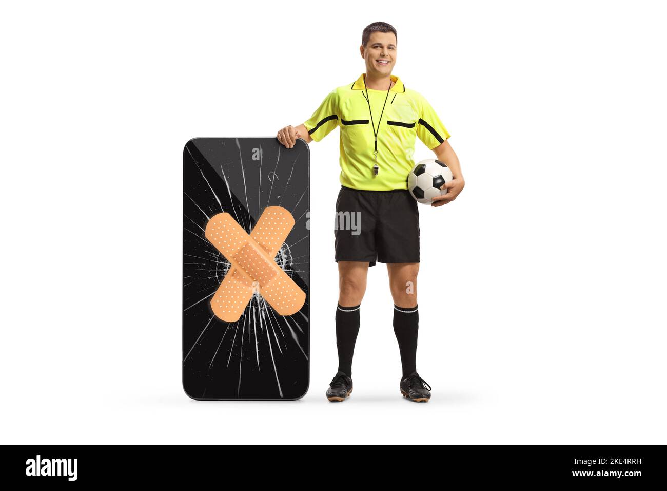 Portrait complet d'un arbitre de football debout à côté d'un smartphone avec écran cassé fixé avec bandage isolé sur fond blanc Banque D'Images