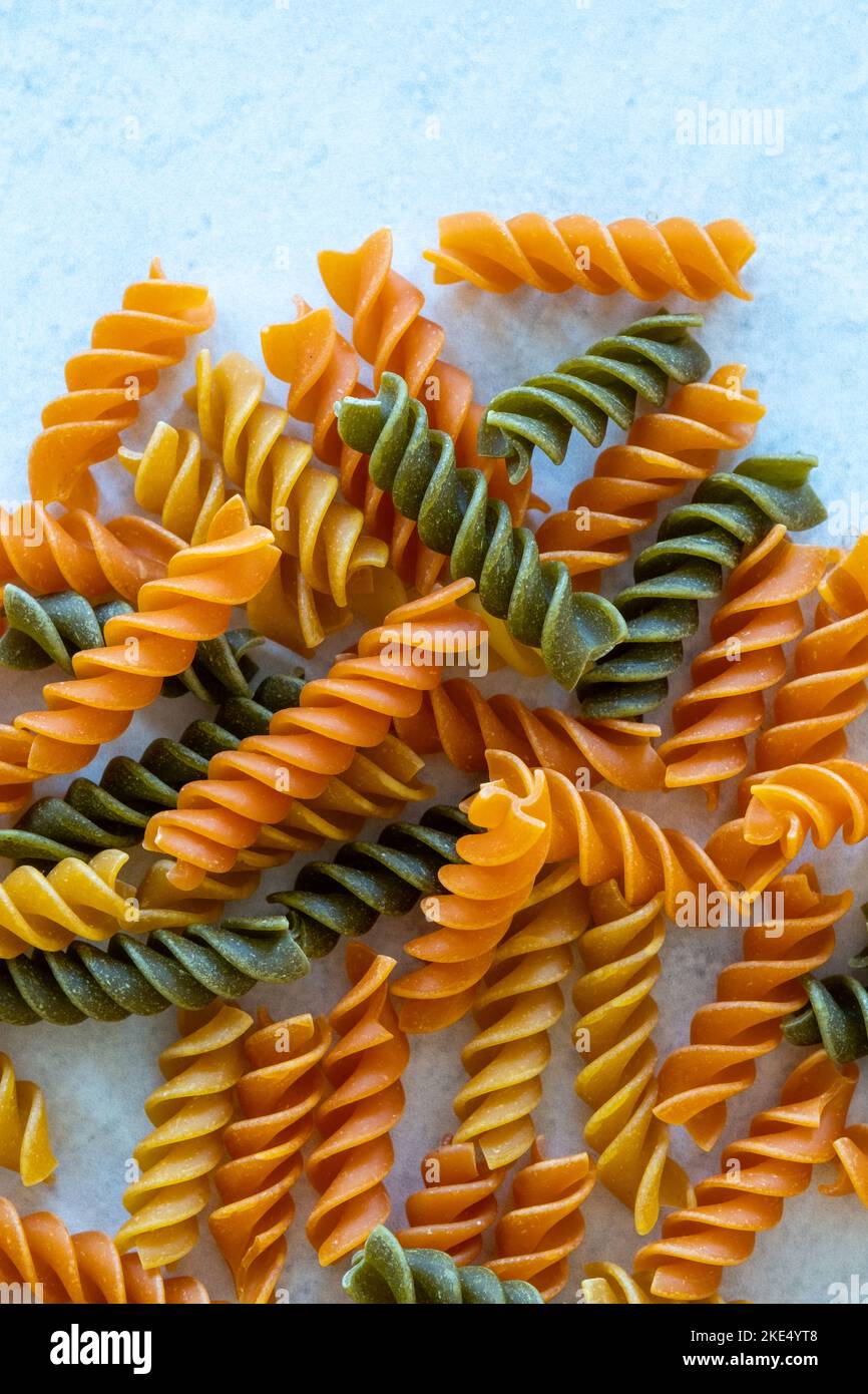 Pâtes tricocolor fusilli sèches sur fond de granit blanc : Banque D'Images