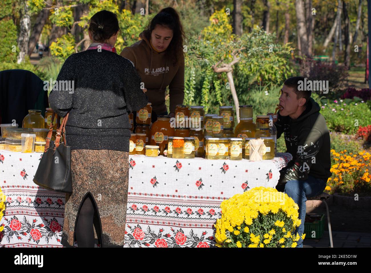 Chisinau, Moldavie - 15 octobre 2022: Beaucoup de différents pots de verre de miel de marque polonaise. Femme achetant du miel Banque D'Images