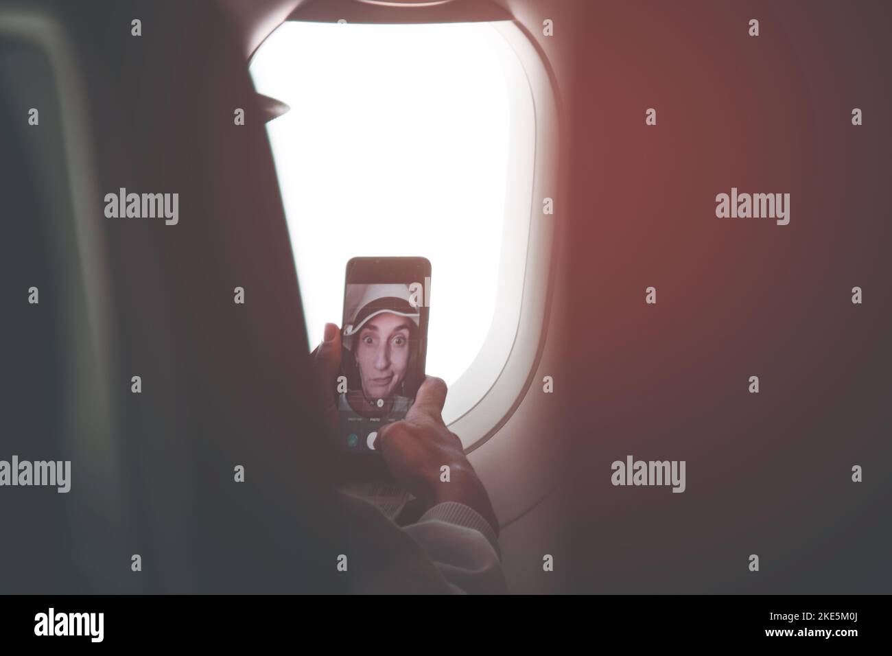 Jeune femme caucasienne pose passager pour selfie écran tactile smartphone dans le siège de cabine d'avion avant le vol. Drôle de filles sur le poste de vacances sur socia Banque D'Images