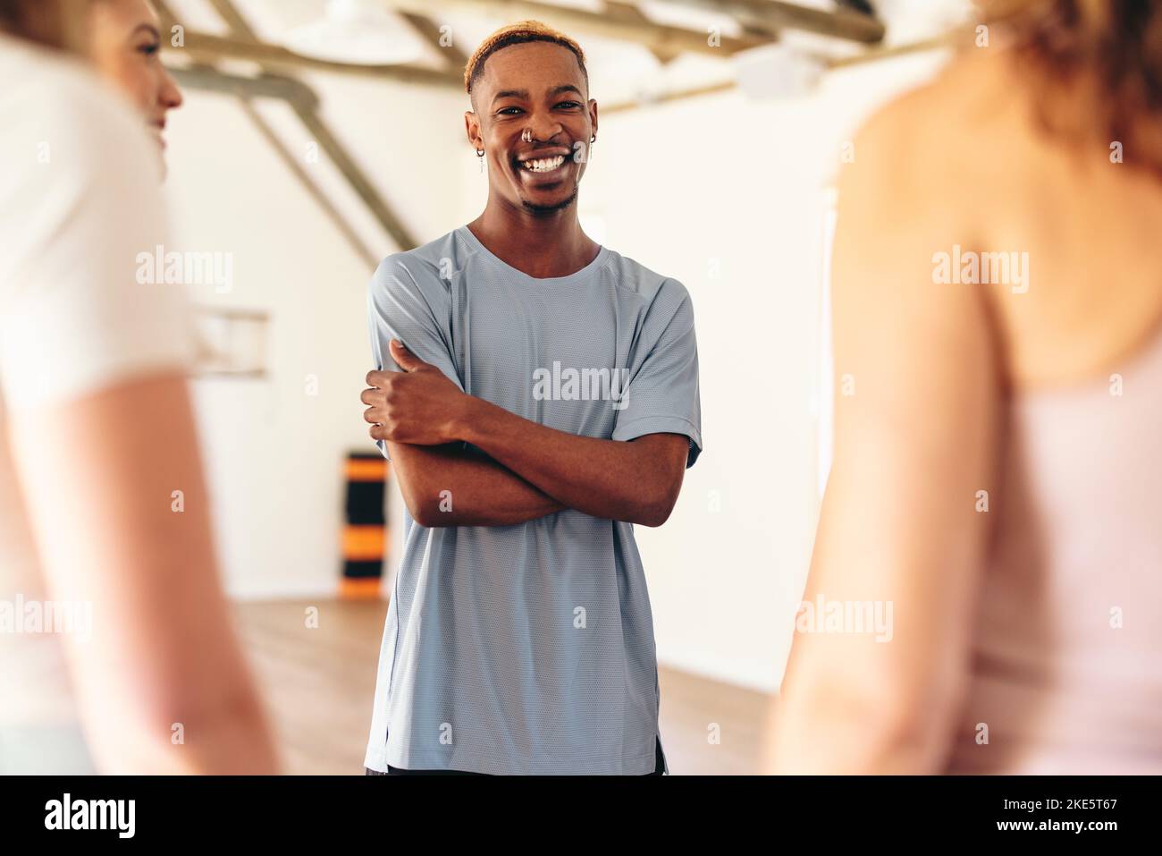 Un jeune homme heureux souriant à la caméra tout en se tenant dans un cercle avec sa classe de yoga. Groupe d'amis multiculturels en forme physique qui parlent entre eux Banque D'Images