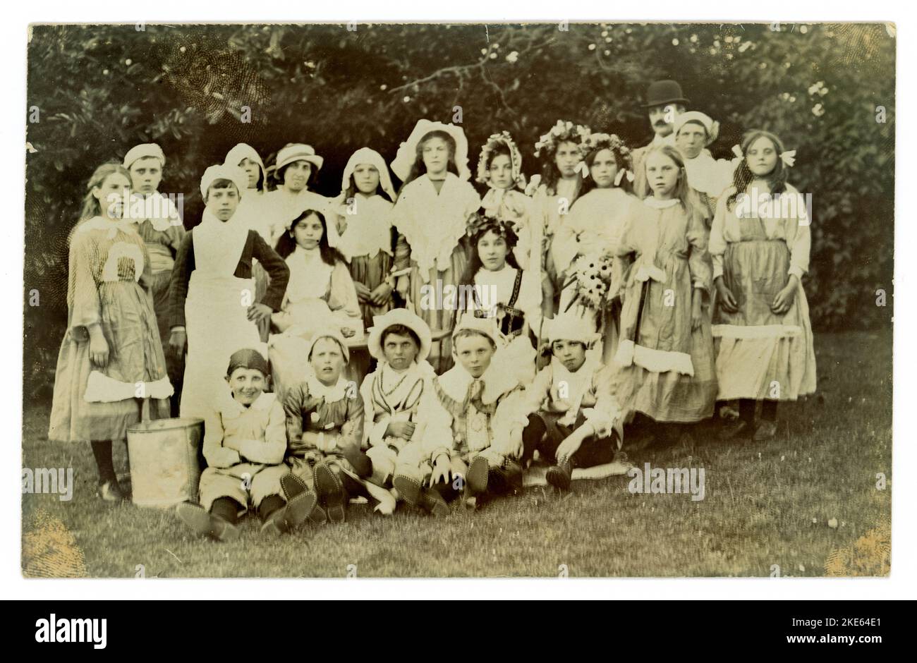Carte postale originale du début des années 1900 d'un groupe d'enfants à l'extérieur portant une robe de fantaisie, un homme semble être habillé comme Charlie Chaplin ou pourrait juste être la mode du jour. Vers 1919 Royaume-Uni Banque D'Images