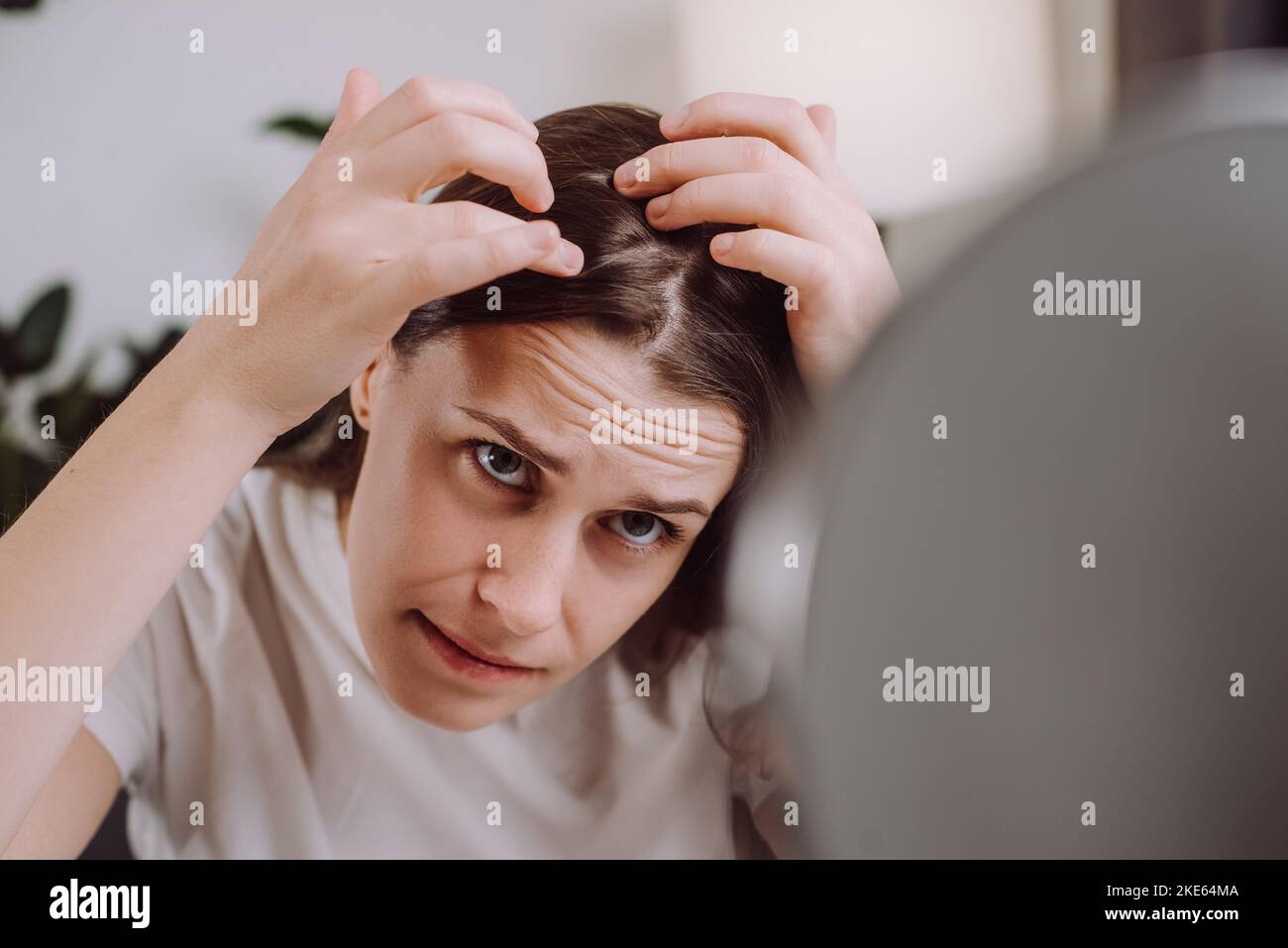 Gros plan de jeunes femmes malheureuses s'inquiètent de regarder le cuir chevelu dans le miroir assis sur le canapé, les mains en rupture dans la perte de cheveux avant, problème mince symptôme à la maison. Banque D'Images