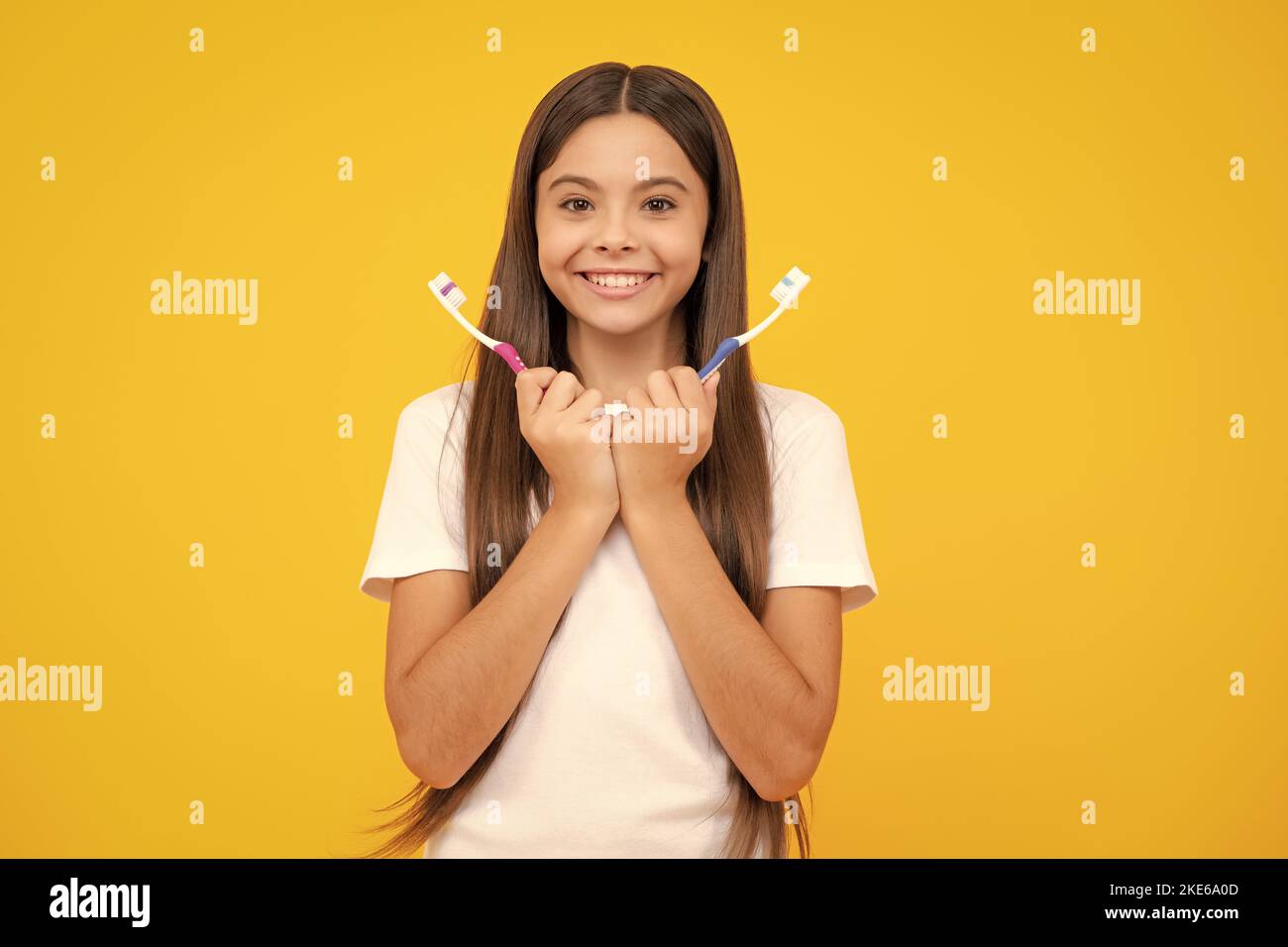 Joyeux portrait d'adolescent. Portrait de la jeune fille caucasienne tient une brosse à dents se brossant ses dents, routine du matin, hygiène dentaire, isolé sur jaune Banque D'Images