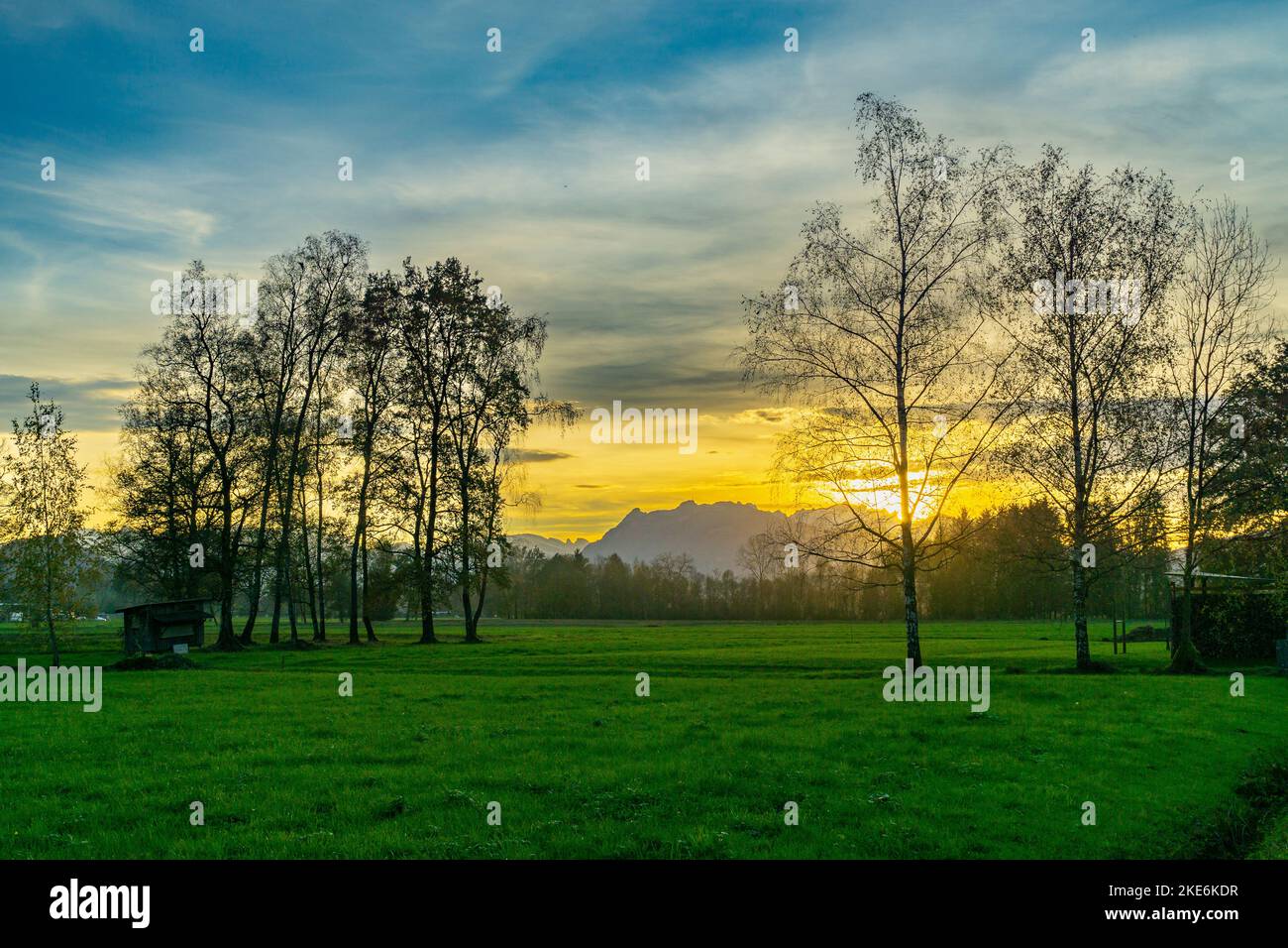Im Rheintal, mit Wiesen und Felder, Bäumen und Schweizer Bergen im hintergrund. Föhn mit Wolken und Blau, gelb, orange, roter Himmel Banque D'Images