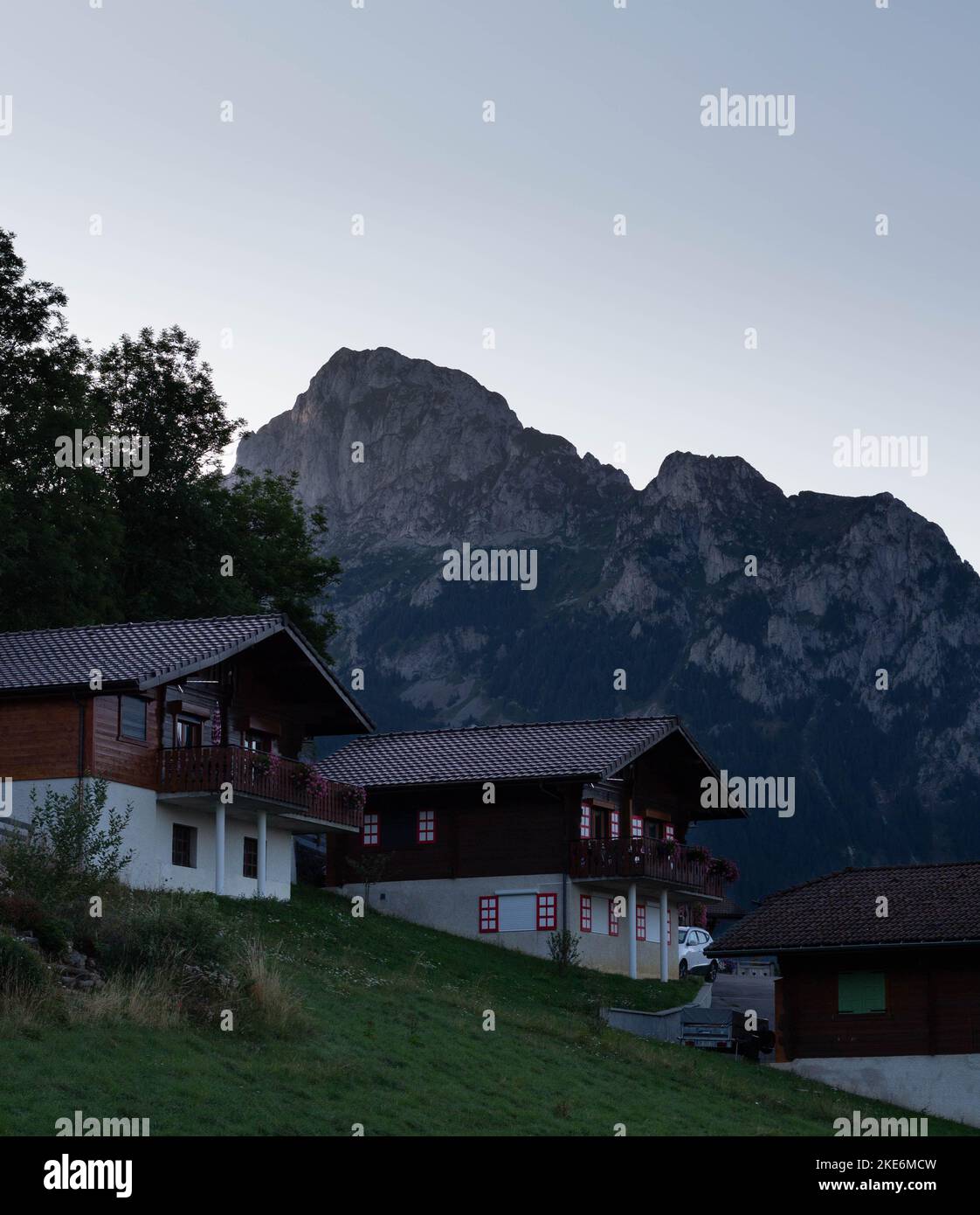 Une photo verticale de maisons de campagne de luxe sur une colline avec un fond de montagnes rugueuses Banque D'Images