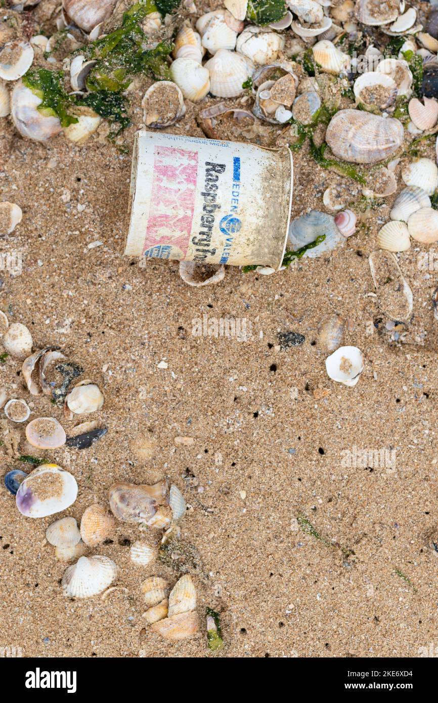 Pot à yaourt en plastique (vieux de plusieurs décennies) lavé sur la plage - Angleterre, Royaume-Uni Banque D'Images