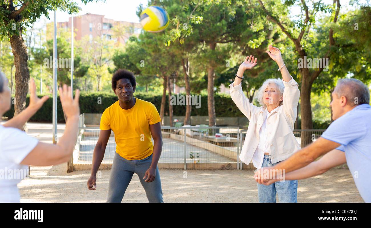 Club social de joyeux personnes âgées diverses appréciant le volley-ball le jour ensoleillé d'octobre plein air Banque D'Images