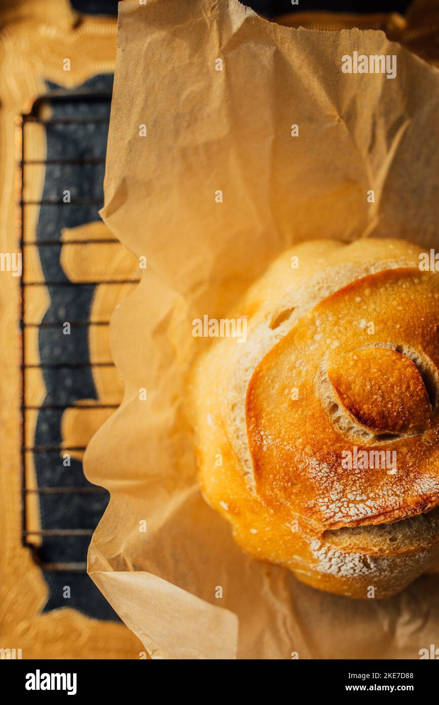 Pain rond fraîchement cuit de pain de levain maison sur papier parchemin brun, motif oeil Banque D'Images