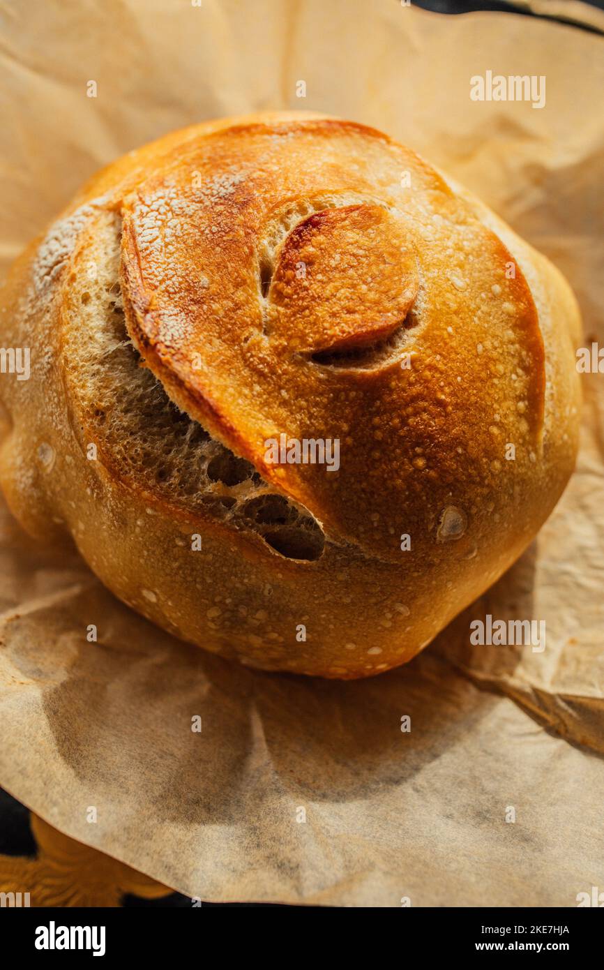 Pain rond fraîchement cuit de pain de levain maison sur papier parchemin brun, motif oeil Banque D'Images