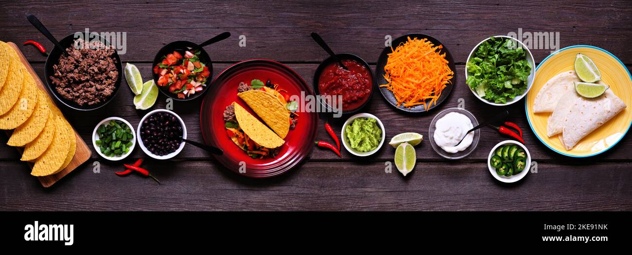 Ambiance de table au bar Taco avec une sélection d'ingrédients. Vue en hauteur sur un arrière-plan de bannière en bois sombre. Buffet de plats mexicains. Banque D'Images