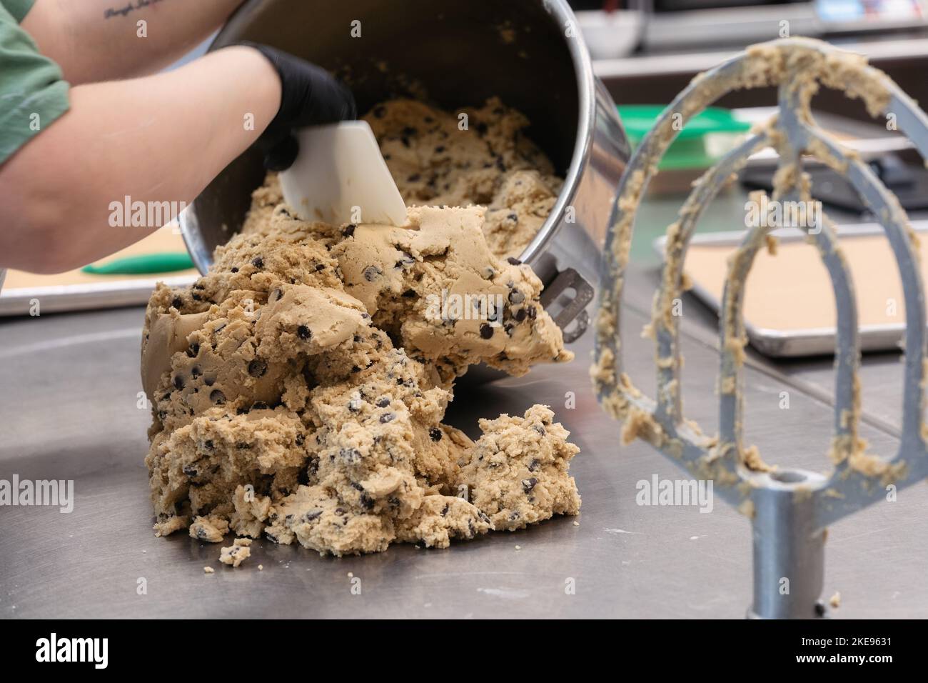 un boulanger cuillères la pâte à biscuits sur une table avec une lame de batteur à proximité Banque D'Images