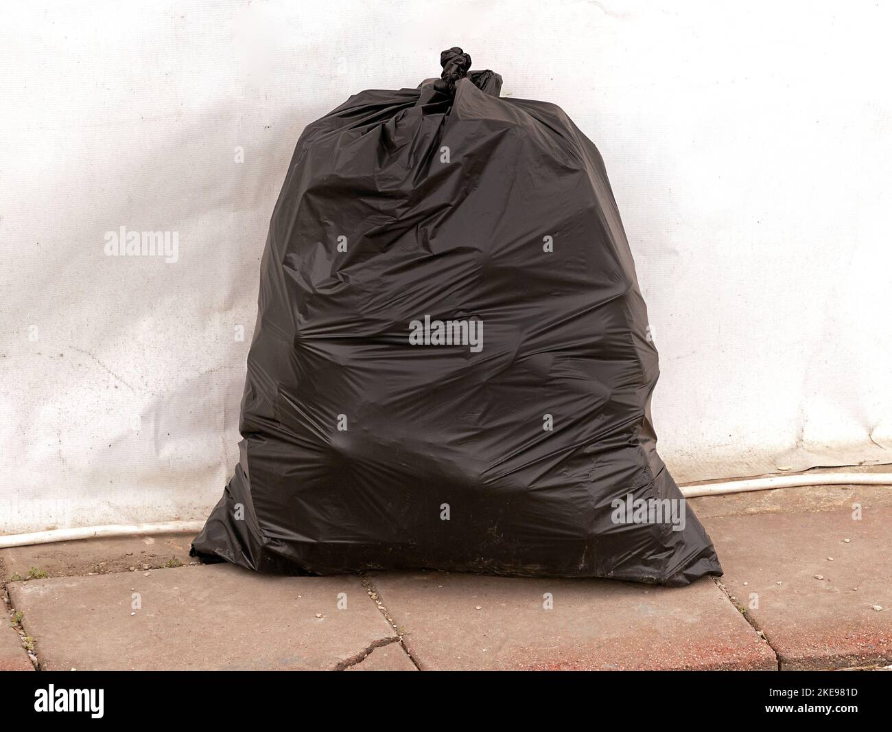 Sac poubelle noir en plastique plein attaché à côté d'un mur à l'extérieur  Photo Stock - Alamy