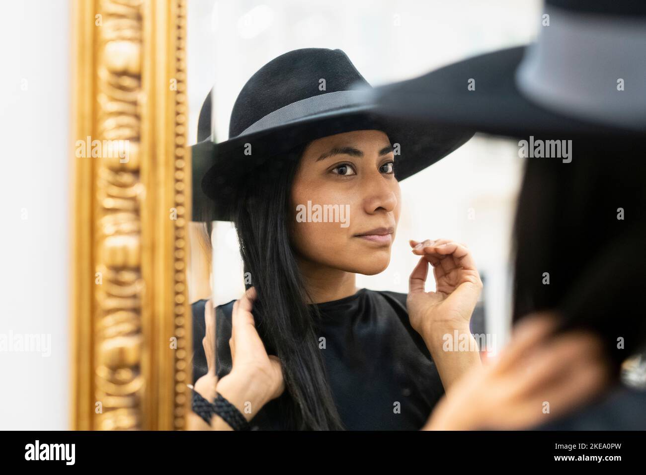 Jeune femme en chapeau noir regardant dans le miroir Banque D'Images