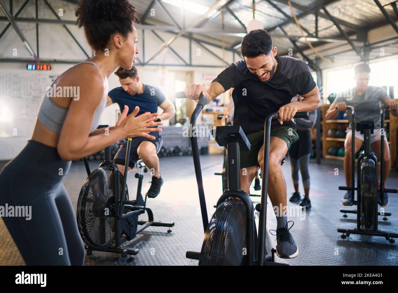 Le vélo, la forme physique et les applaudissements d'un entraîneur avec la motivation pour l'entraînement de gym de vélo. Un entraîneur sportif se claquant pour l'entraînement, le bien-être et le vélo Banque D'Images