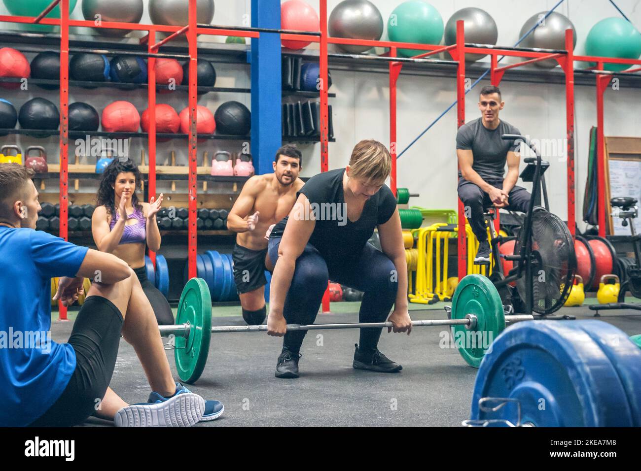 Une femme prête à faire des poids de levage tandis que ses amis de gym l'applaudissent Banque D'Images