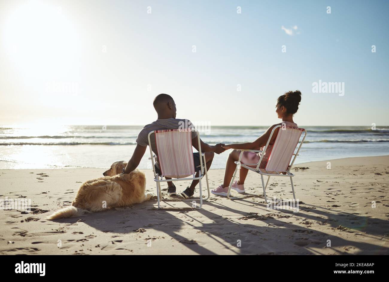 L'amour, le chien ou la famille noire tenant les mains près de la plage, de l'océan ou de la mer pour parler au coucher du soleil, se lier ou se détendre le jour d'été. Famille, voyage ou femme noire Banque D'Images