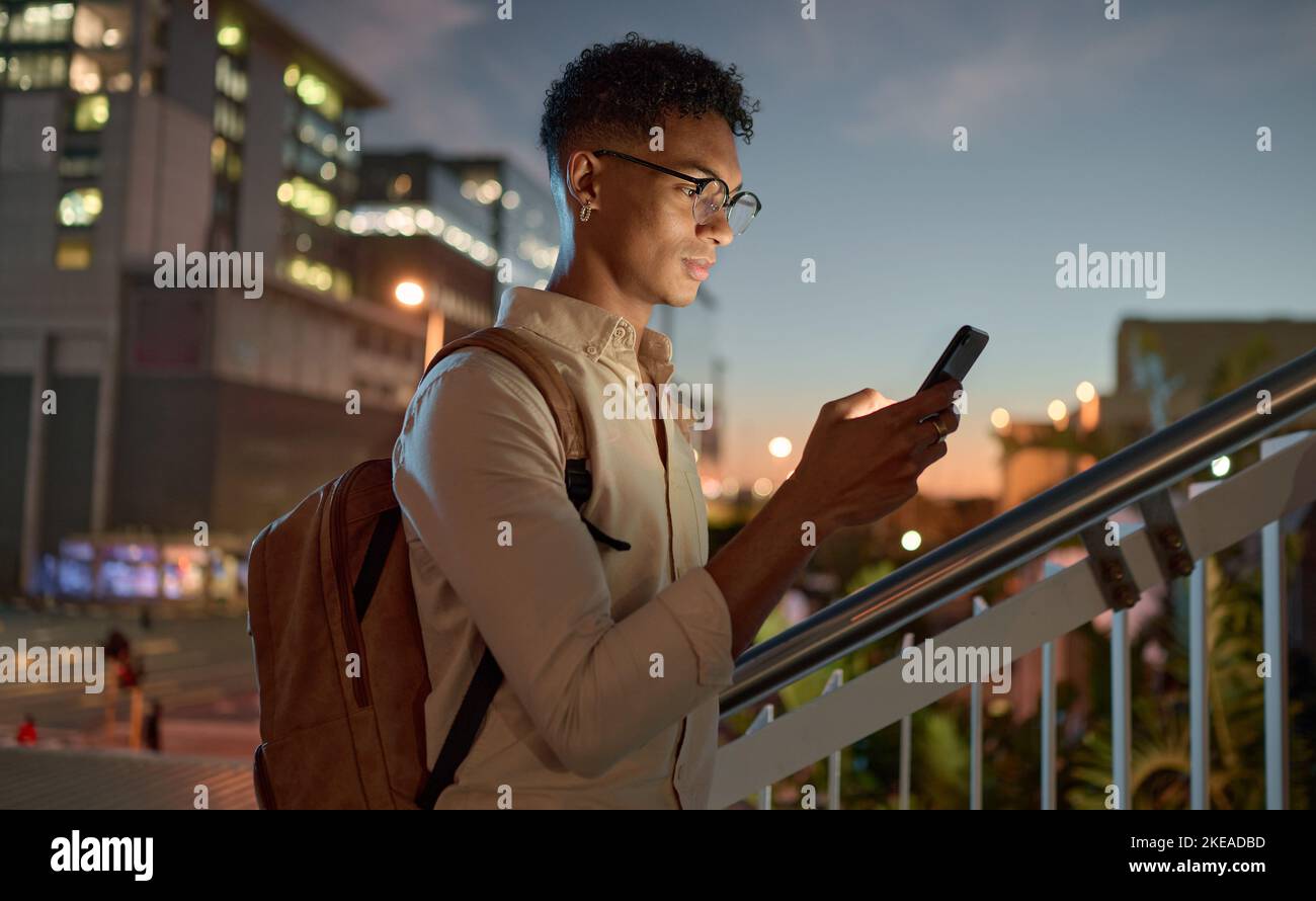 Homme, ville et texte de téléphone d'un étudiant sur l'application de médias sociaux, Internet ou la recherche Web. Homme noir avec la technologie mobile dans le noir de la lecture en ligne Banque D'Images