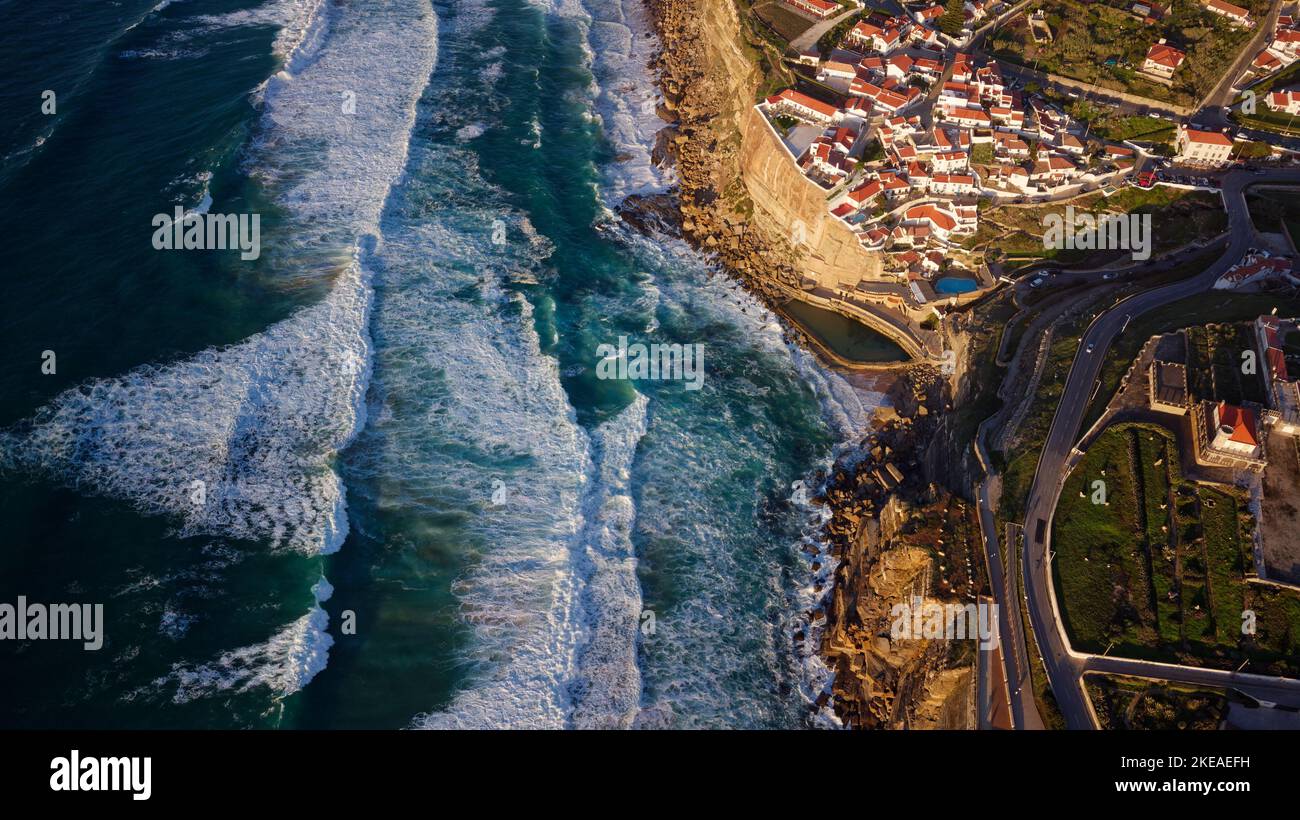 Vue aérienne par drone d'Azenhas do Mar, Portugal. Piscine naturelle dans l'océan, à côté de la falaise et d'un village en bord de mer au coucher du soleil. Meilleures destinations. Banque D'Images