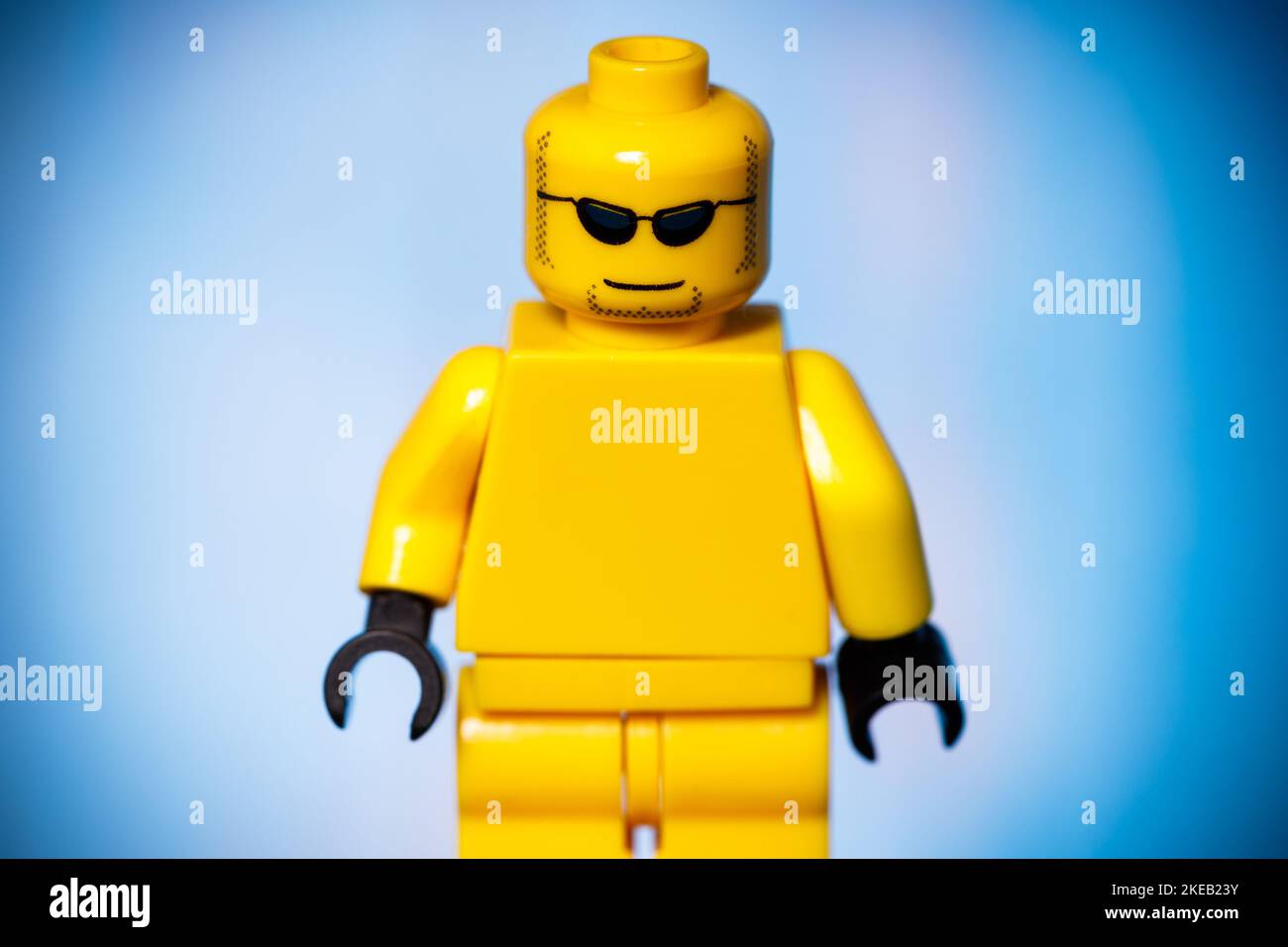 figurine lego jaune avec un visage sarcastique sur fond bleu. Photo de haute qualité Banque D'Images