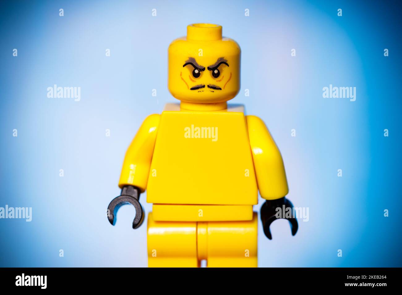 figurine lego jaune avec un visage en colère sur fond bleu. Photo de haute qualité Banque D'Images