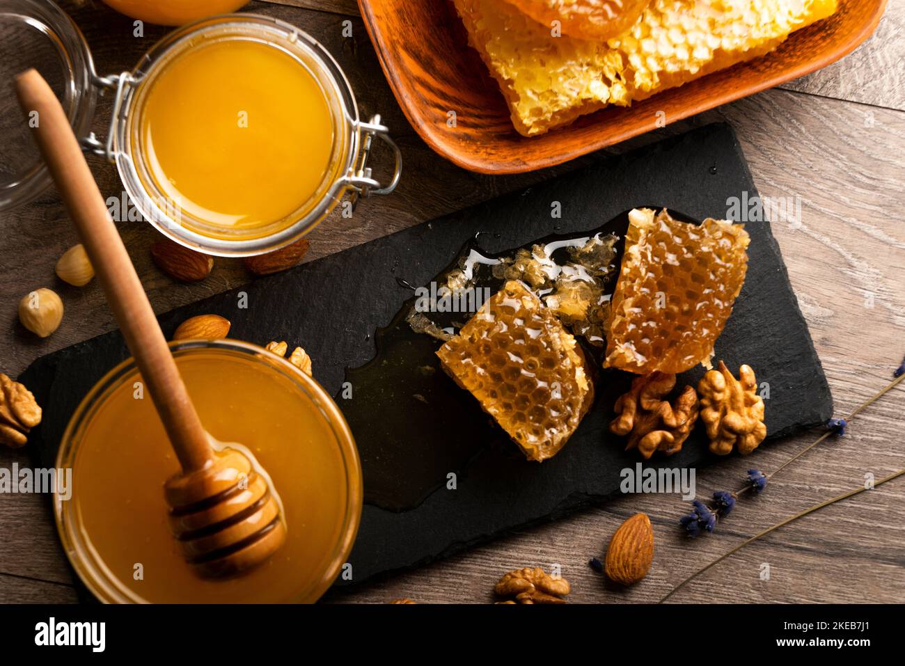 Nid d'abeille sur plateau en ardoise avec miel et noix sur la table de cuisine Banque D'Images