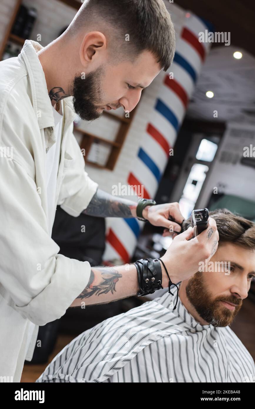 Tatouage coiffeur taille cheveux de l'homme barbu dans barbershop, image de stock Banque D'Images