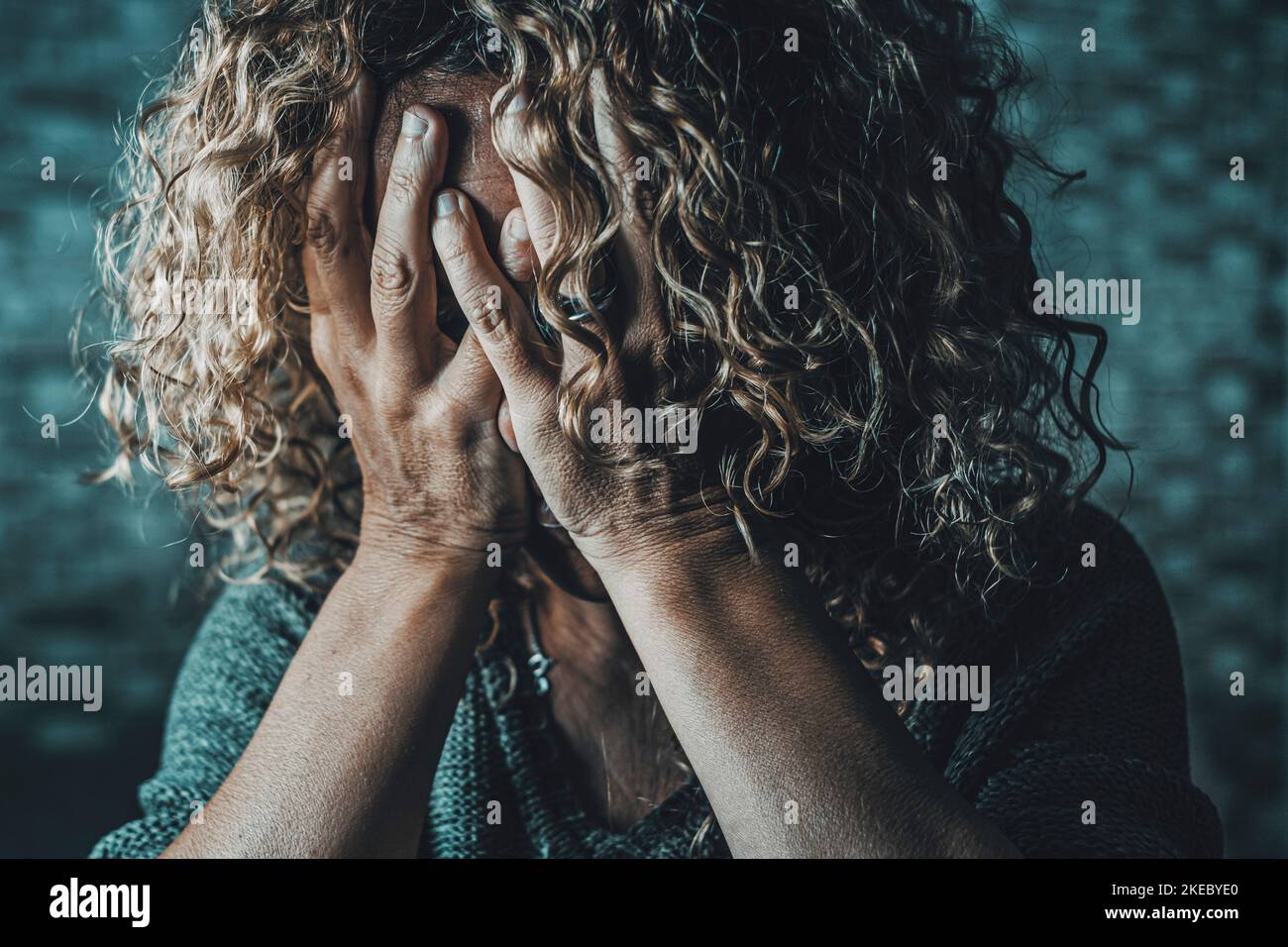 Gros plan d'une femme désespérée avec les mains sur le visage dans l'obscurité à la maison. Situation de la criminalité liée à la violence sexuelle dans la famille. Pleurs femelles stressées et effrayées. Solitude et dépression les gens souffrent de maladies santé. Tristesse Banque D'Images