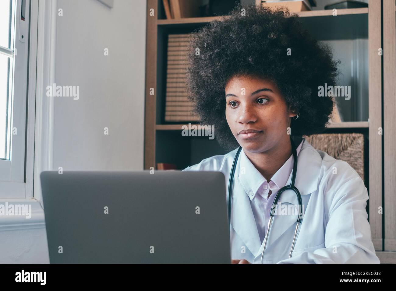 Femme médecin professionnel portant un uniforme consultant patient client en ligne par appel vidéo regardant l'écran d'ordinateur portable. Femme afro-américaine de soins de santé utilisant un ordinateur portable à la clinique médicale Banque D'Images
