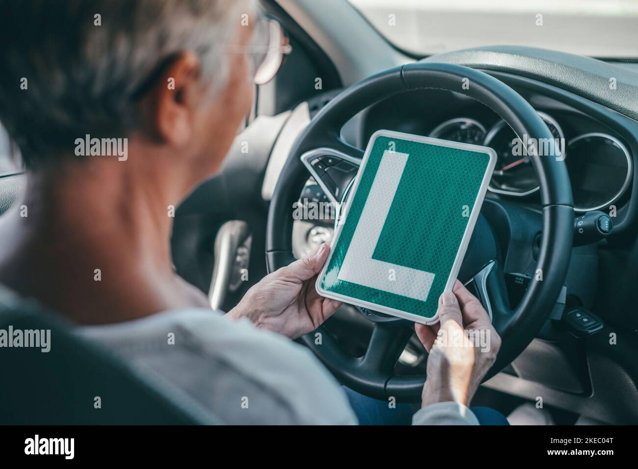 Une vieille femme qui obtient le pass pour conduire une voiture à l'âge mûr. Senior regardant le permis L dans le siège conducteur Banque D'Images