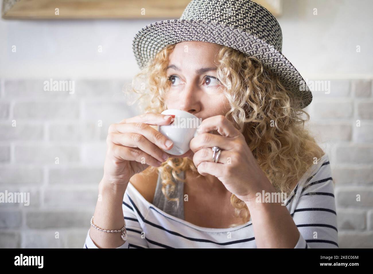 belle femme en forme de curly buvant un café seul au bar regarder loin - portrait et gros plan d'un adulte Banque D'Images