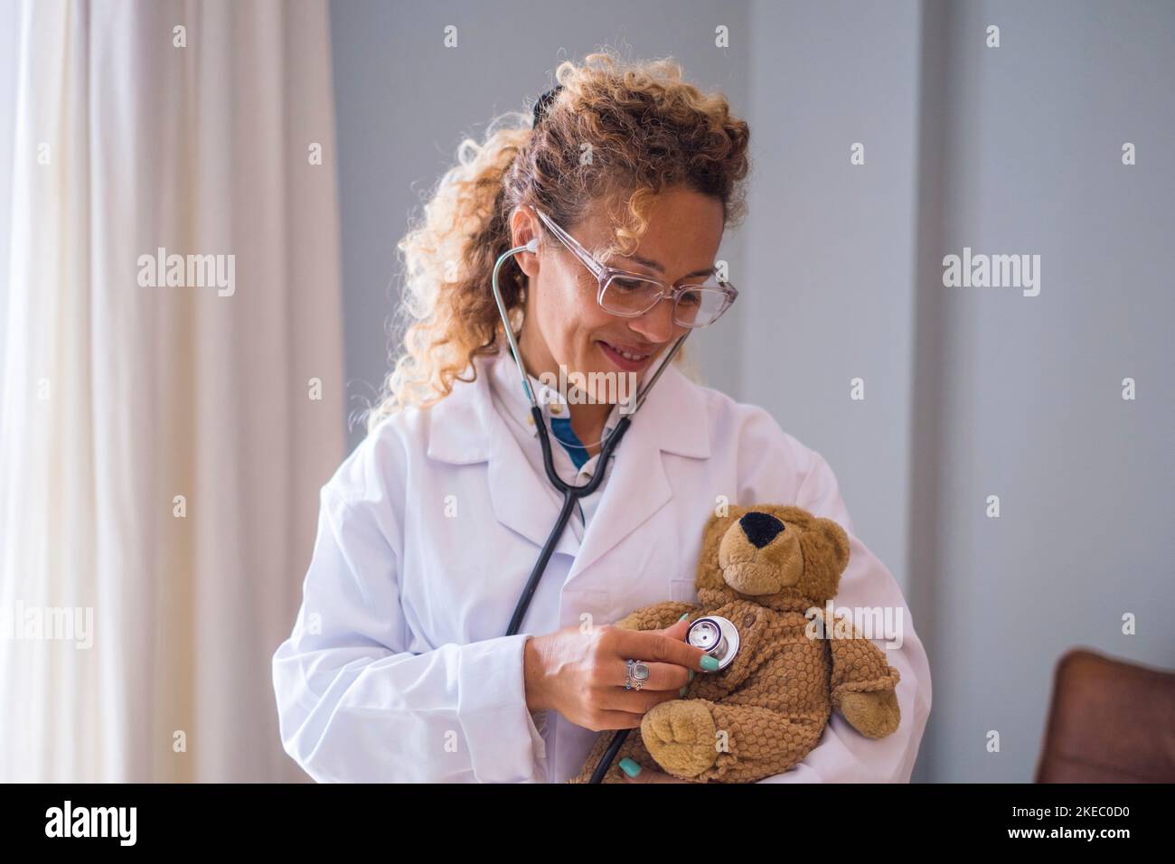 Bonne jeune femme médecin en uniforme en vérifiant l'ours en peluche avec stéthoscope à la clinique. Professionnel de la santé ou professionnel de la santé confiant qui examine l'ours en peluche à l'hôpital Banque D'Images