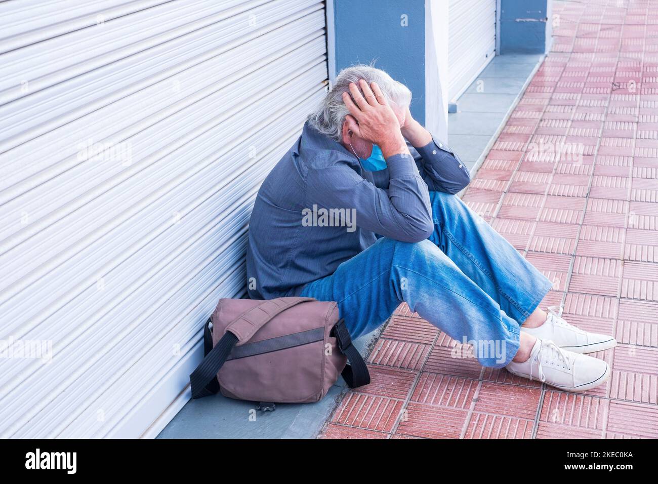 portrait d'un homme ou d'un aîné triste et contrarié assis à l'extérieur d'un magasin fermé après avoir fermé ses activités et perdu son emploi pour le covid-19 - crise après la quarantaine problème économique Banque D'Images