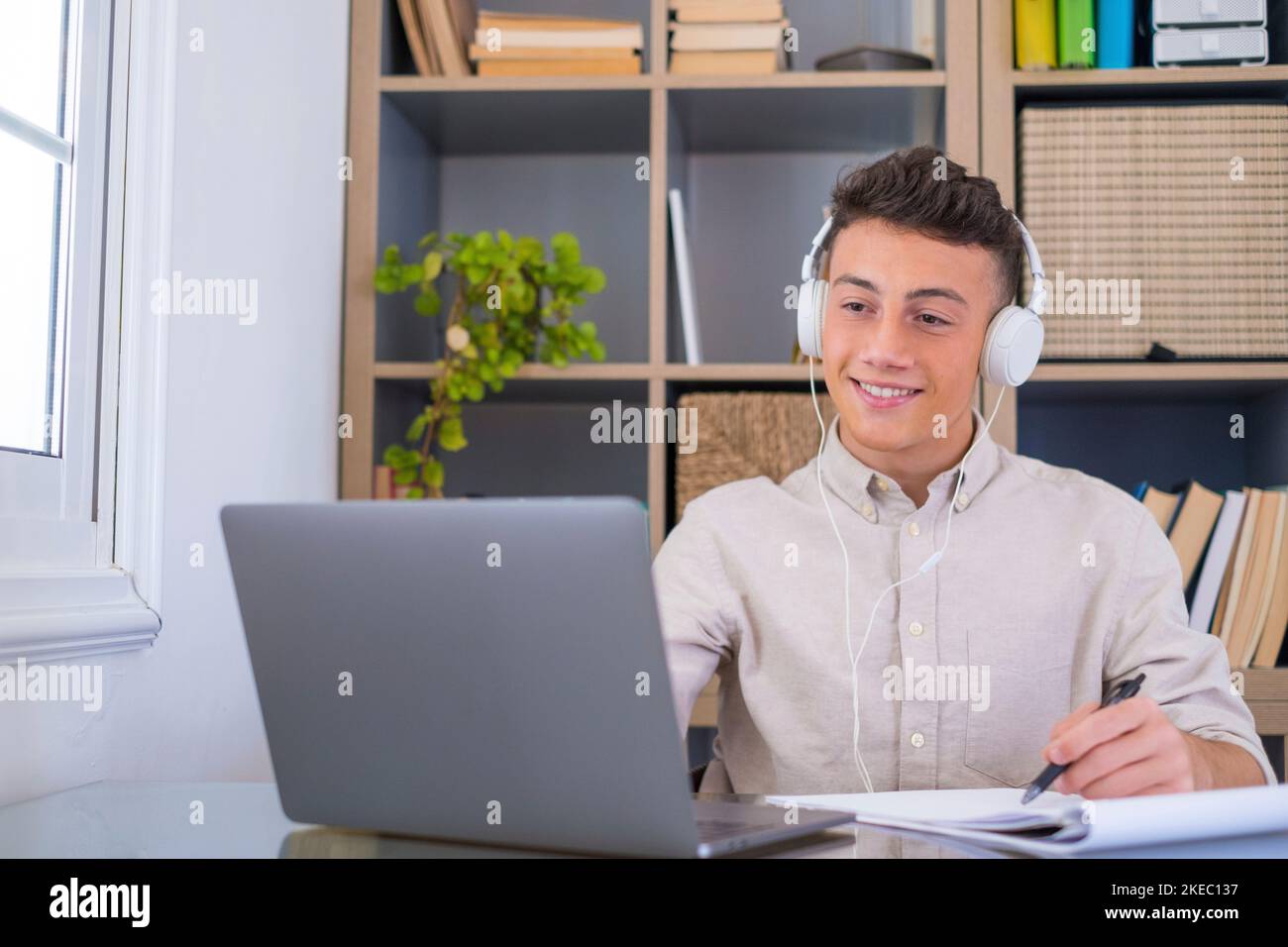 Joyeux adolescent du millénaire détendu homme d'affaires porter un casque sans fil regarder loin repos sur le lieu de travail terminé travail écouter la musique podcast sentir la tranquillité d'esprit concept assis au bureau dans un bureau ensoleillé écrit Banque D'Images