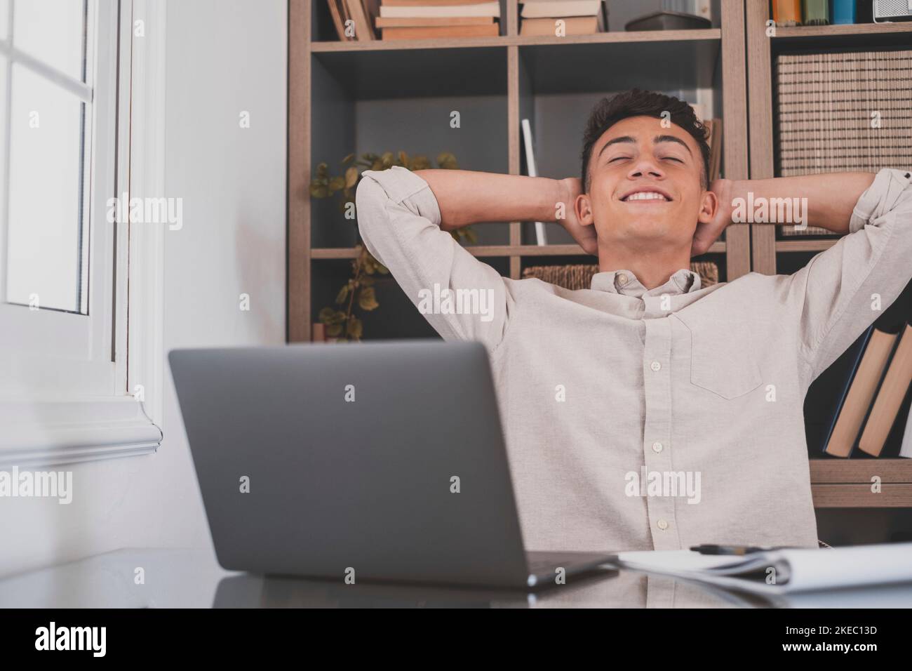 Heureux satisfait caucasien homme de repos à la maison bureau s'asseoir avec le portable tenir les mains derrière la tête, jeune adolescent rêveur se détendre travail fini se sentir la tranquillité d'esprit regarder loin rêve penser à la réussite future concept Banque D'Images