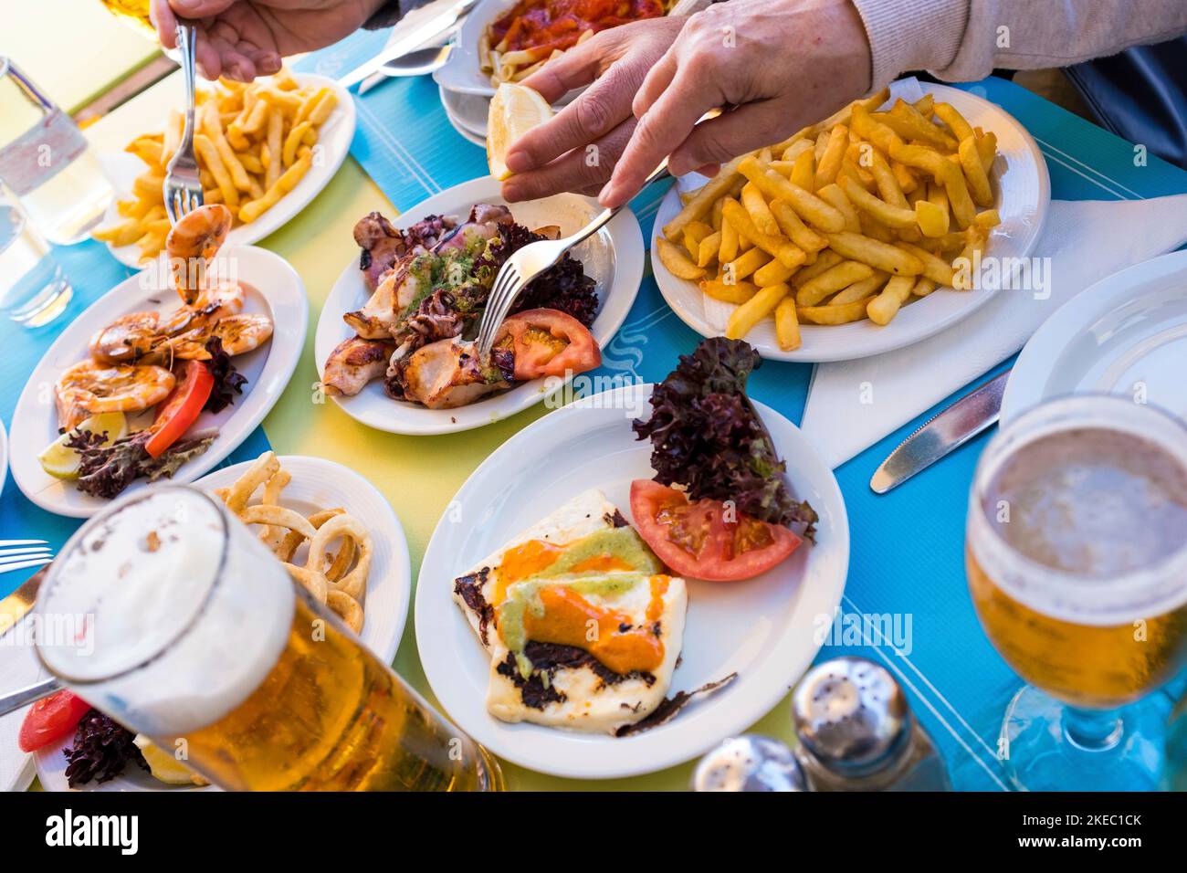 table avec de la nourriture marine comme le poisson - gros plan et portrait des mains prenant la nourriture du milieu de la table - restaurant à la plage Banque D'Images