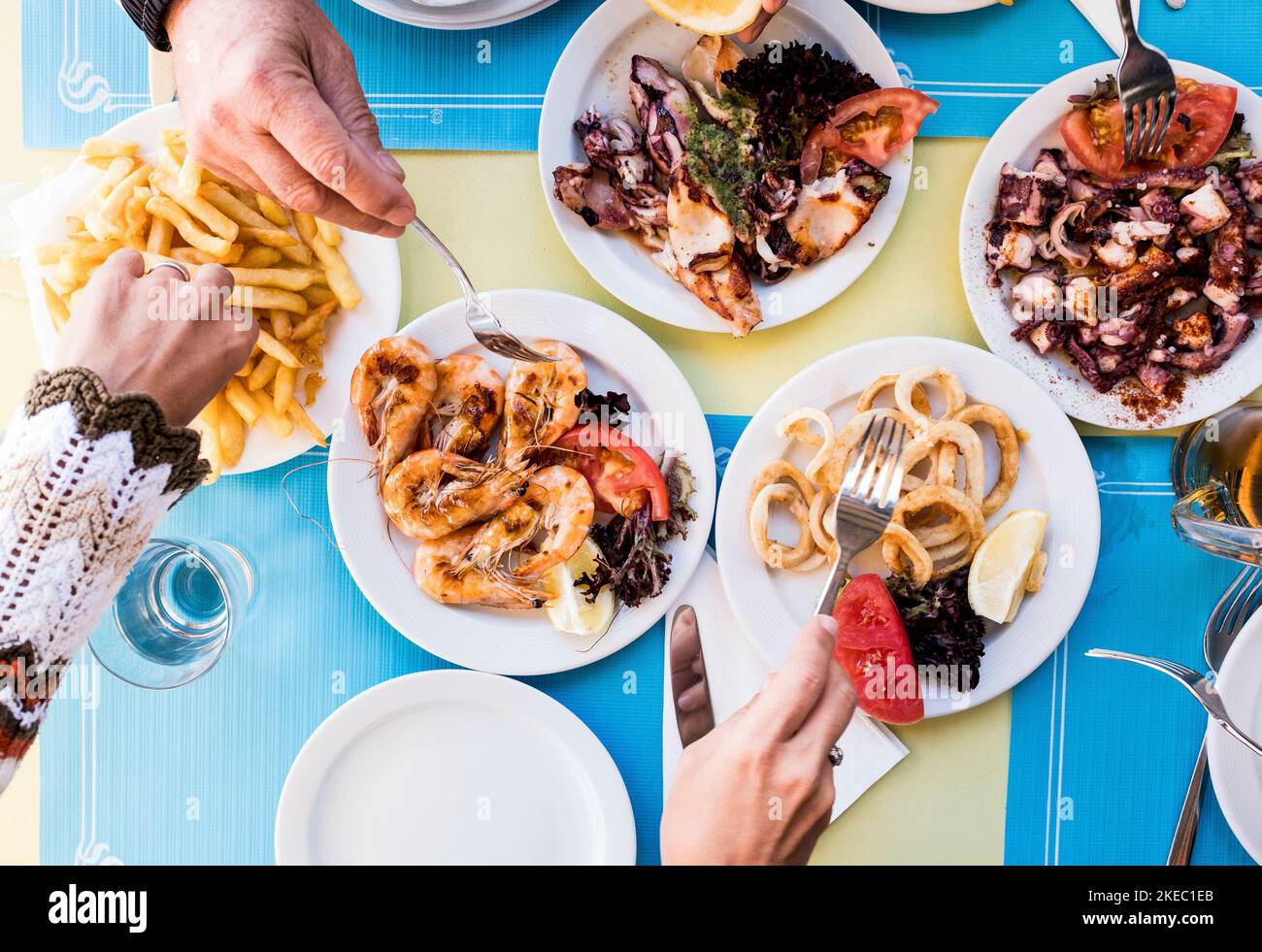 table pleine de nourriture au déjeuner - poissons marins et nourriture saine - au-dessus et vue de dessus - quelques mains prenant la nourriture du milieu de la table Banque D'Images