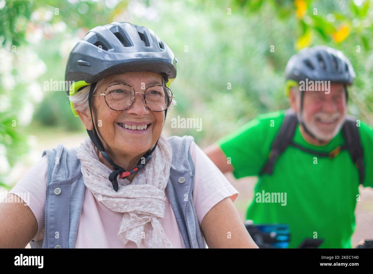 Portrait d'une vieille femme souriant et appréciant la nature en plein air à vélo avec son mari riant. Tête de lit de la femme adulte avec des lunettes se sentant en bonne santé. Banque D'Images