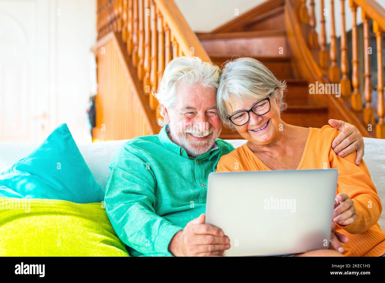 couple de deux personnes matures et âgées heureux ou aînés à la maison assis sur le canapé profiter et s'amuser ensemble en regardant et en utilisant un ordinateur portable ou un pc d'ordinateur Banque D'Images