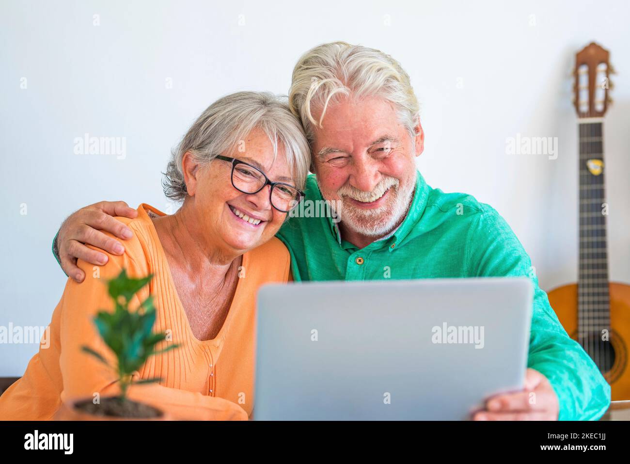 couple de deux personnes matures et âgées heureux ou aînés à la maison assis sur le canapé profiter et s'amuser ensemble en regardant et en utilisant un ordinateur portable ou un pc d'ordinateur Banque D'Images